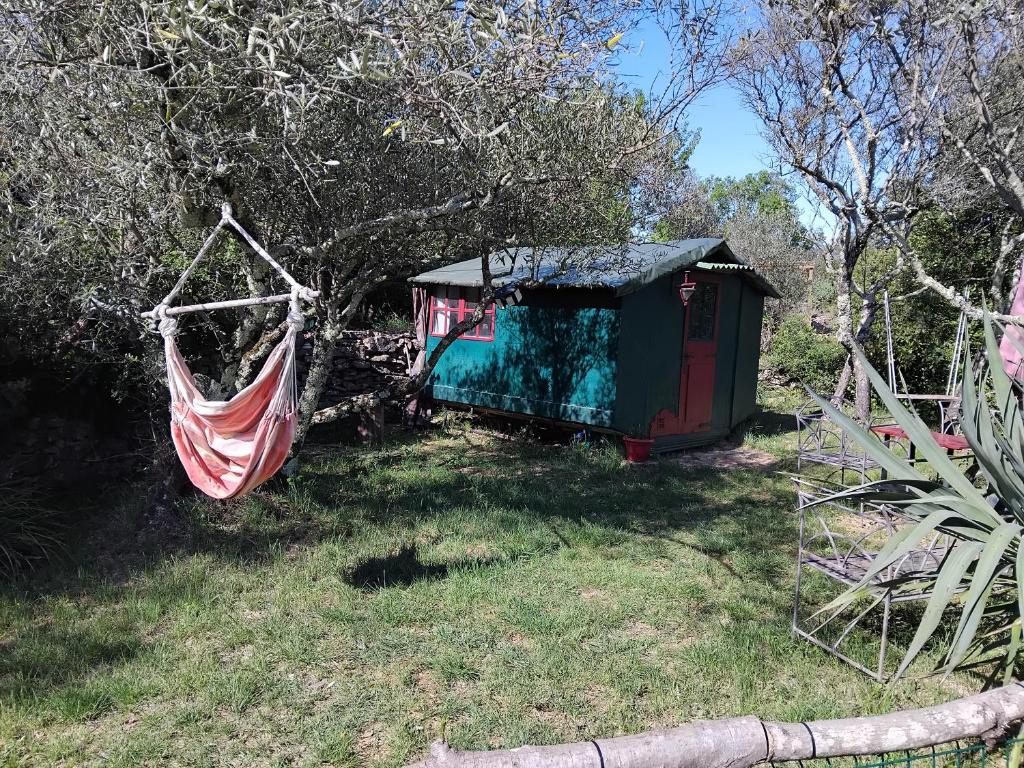 a hammock hanging from a shed in a yard at Cabane sous les oliviers in Saint-Ambroix