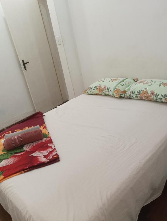 a white bed in a small room with pillows on it at Quarto 02 in Montes Claros