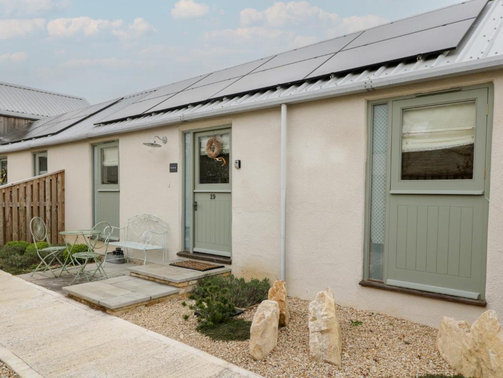 a white house with green garage doors at The Little Loft in Burford