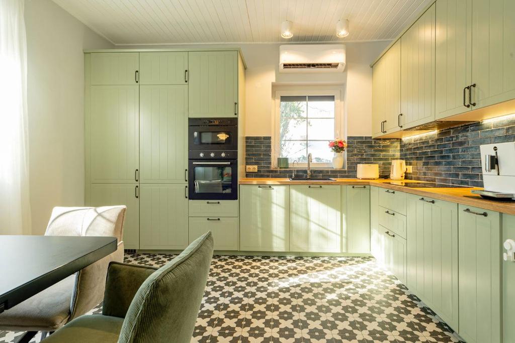 a kitchen with white cabinets and a table and chairs at Ágnes Villa Balatonföldvár in Balatonföldvár