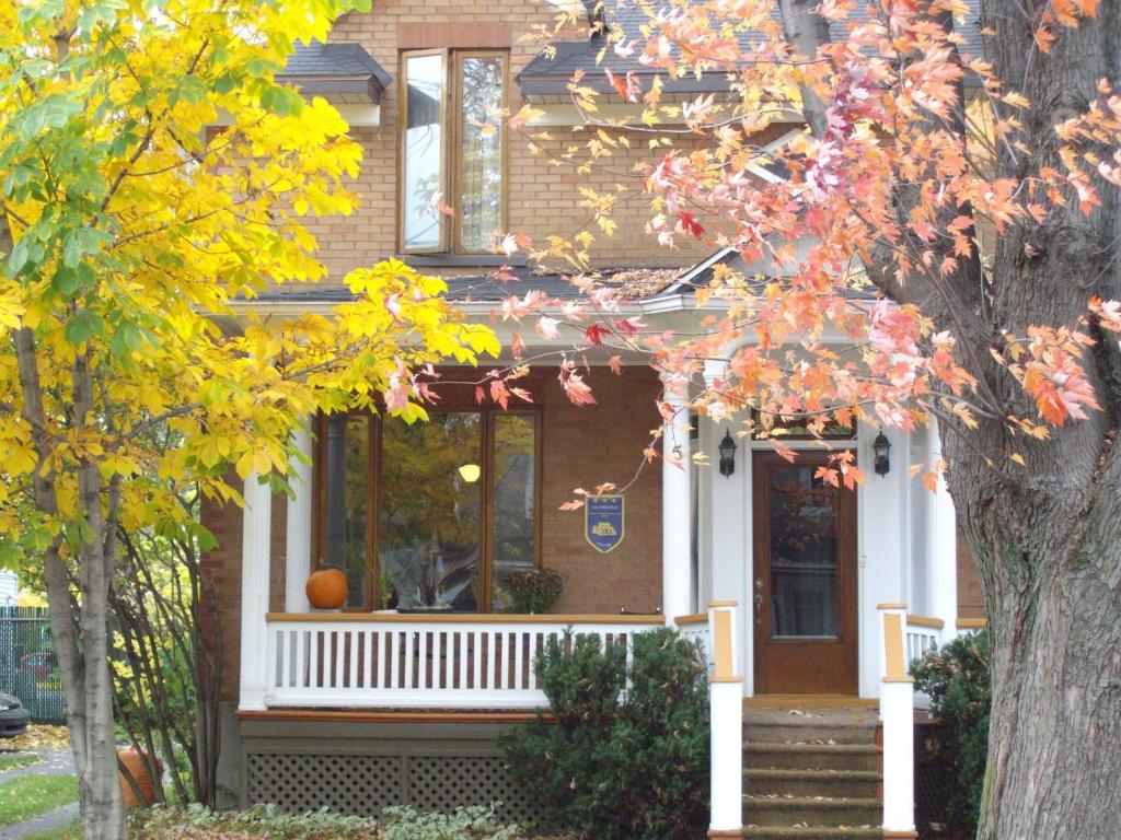 una casa con un porche blanco y un árbol en Aux Années Folles, en Quebec