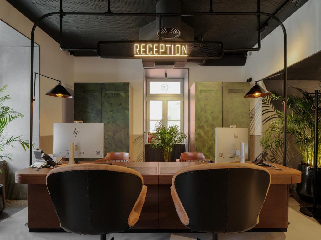 The reception desk sits beneath a prominent sign in a plant-filled, industrial-style lobby.