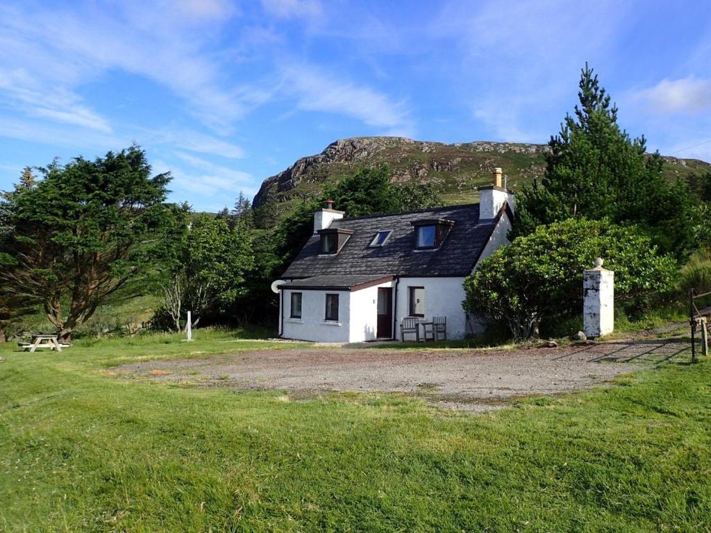 a white house with a mountain in the background at 2 Bed in Lairg oc-75909 in Badcall