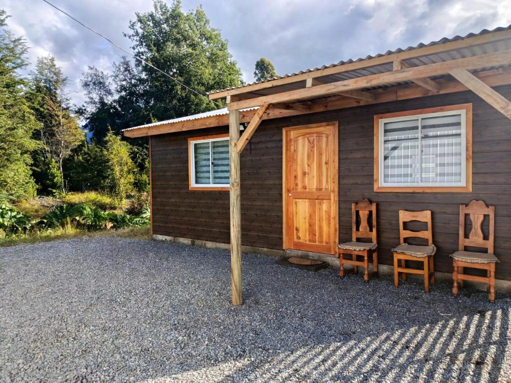 a cabin with two chairs in front of it at cabaña zoila N in Coñaripe