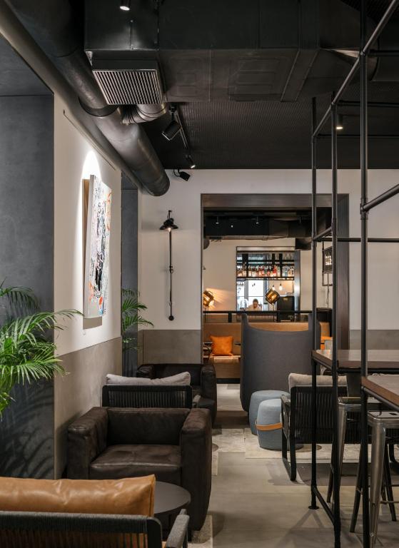 A narrow lobby lounge with layered seating, tables and a bar visible beyond.