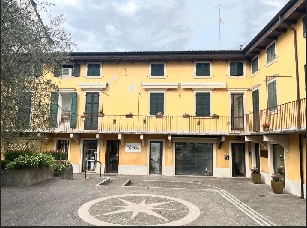 a large yellow building with a clock in a parking lot at Residenza Arilica - Silkeys in Peschiera del Garda