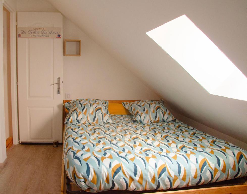 a bed in a attic room with a window at Le Relais de Louis in Orbigny