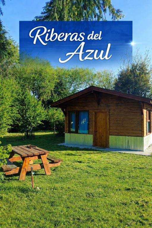 a picnic table in the grass in front of a cabin at Riberas del Azul in Lago Puelo