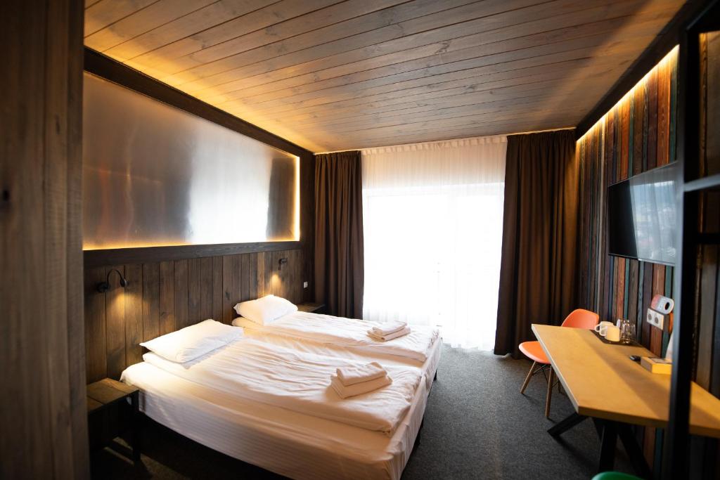 a hotel room with a bed and a desk and a television at Loft & SPA resort ROOMs in Palyanytsya