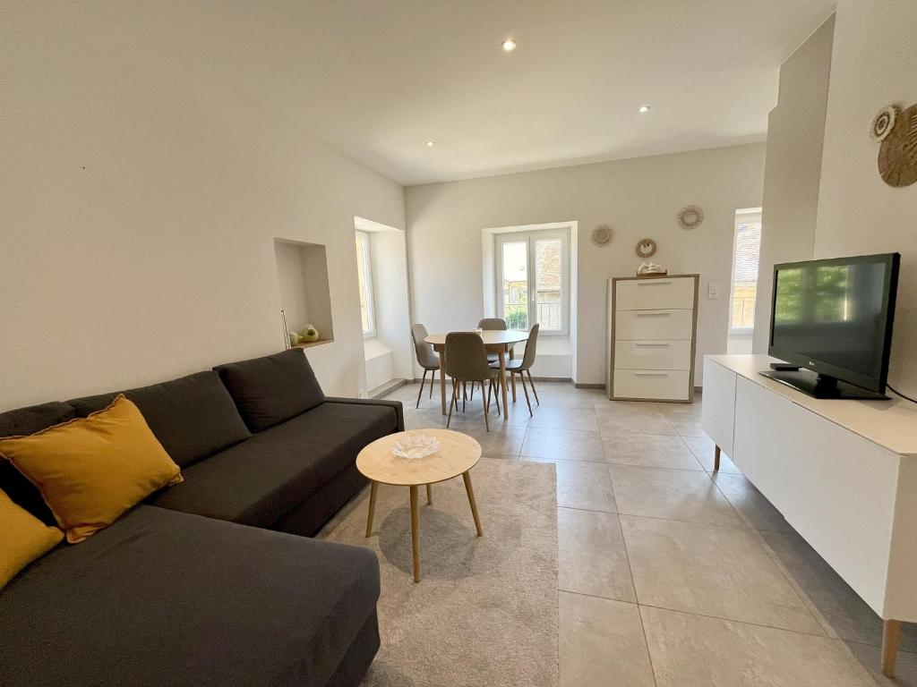 ein Wohnzimmer mit Sofa, Fernseher und Tisch in der Unterkunft HostHelp - Les Balises in Bevaix