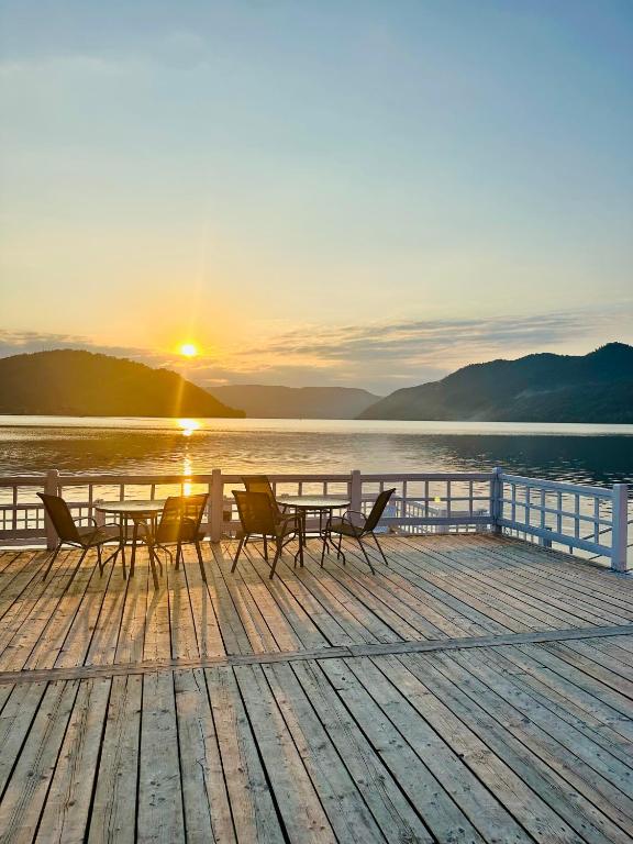 a table and chairs on a dock with the sunset at NOAH ponton in Orşova