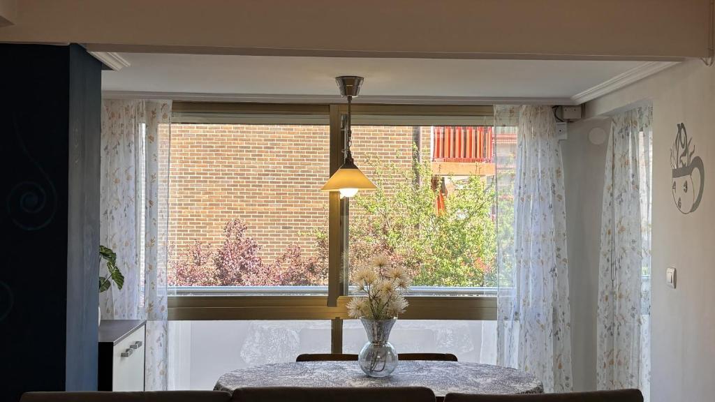 a table with a vase of flowers in front of a window at Mitxelena in Zarautz
