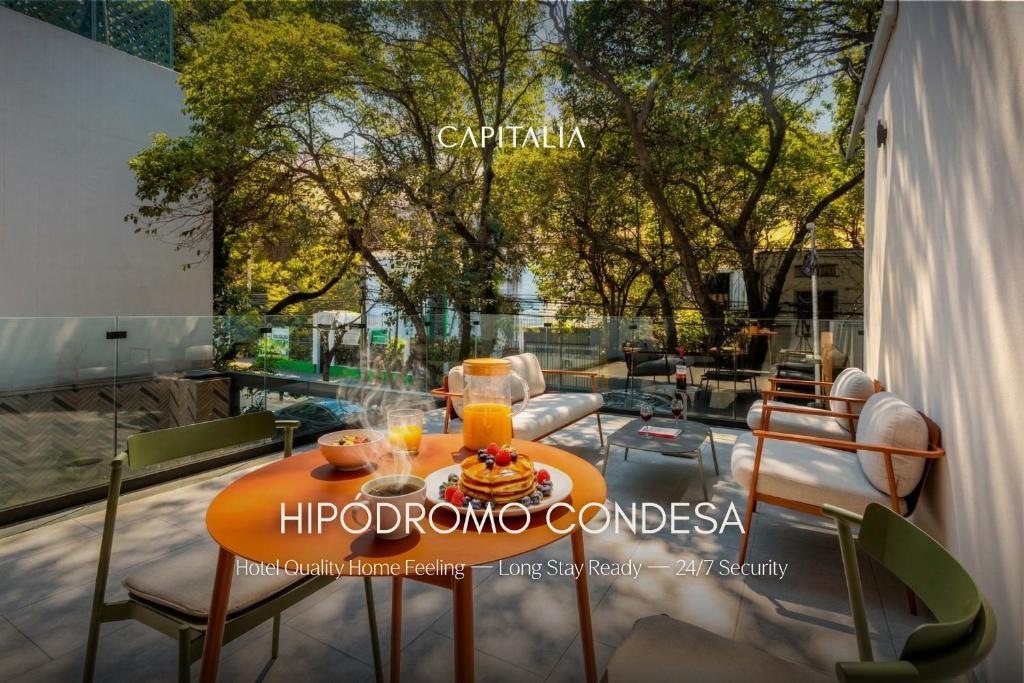 a table with a plate of food and orange juice at Capitalia Hipodromo Condesa in Mexico City