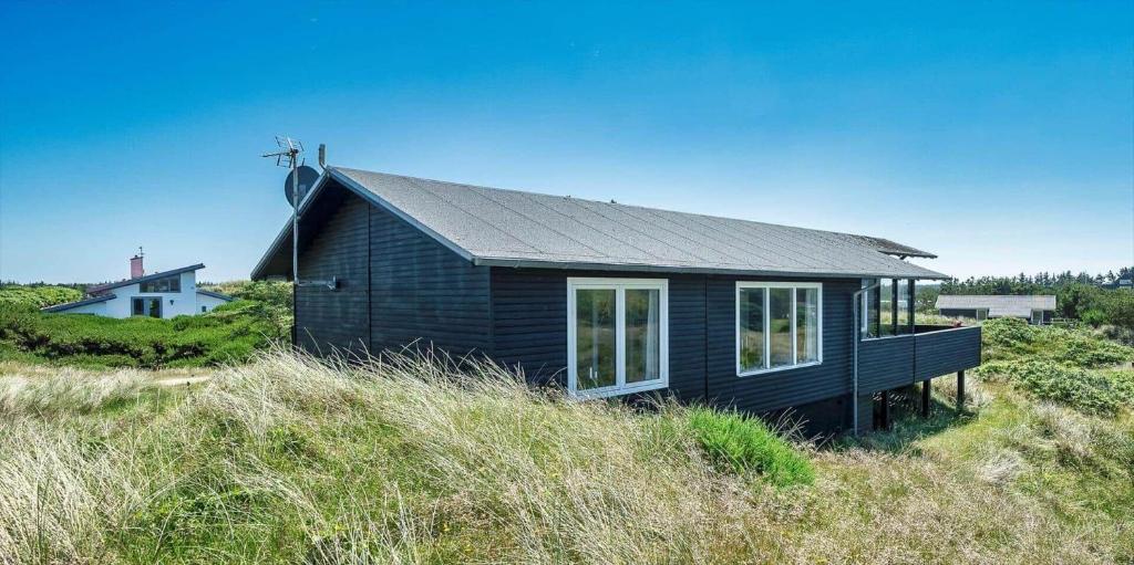 a black house sitting on top of a hill at VE072-Vejers-Strand-Violvej-9 in Vejers Strand