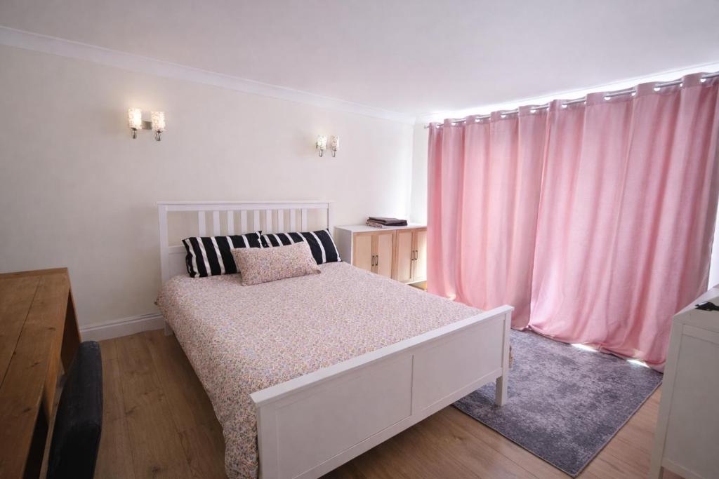 a white bedroom with a bed and pink curtains at ValueStays Chalvey Free Parking in Slough