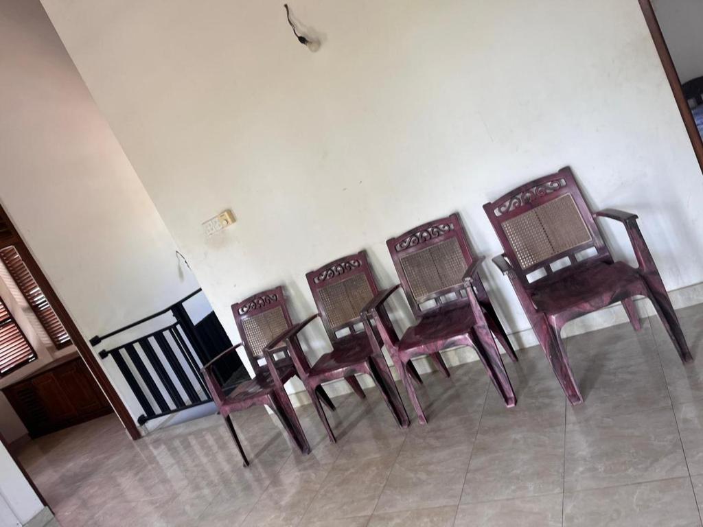 a row of chairs lined up against a wall at Dissanayaka house in Nikawatawana
