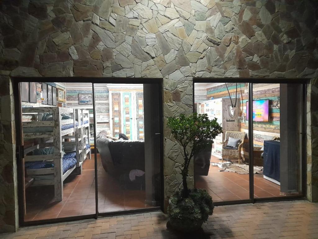 a living room with a stone wall and two glass doors at Stadion Sleepover Cabin in Sasolburg