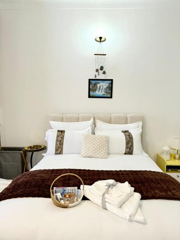 a white bed with a basket of towels on it at The Reset Stay in Kampala