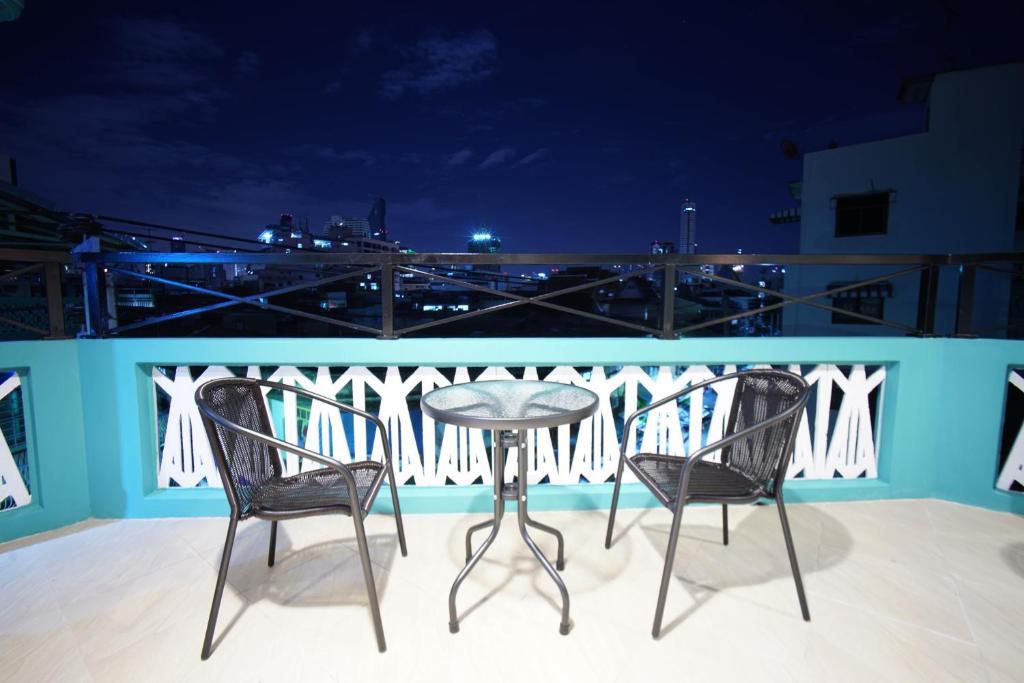 two chairs and a table on a balcony at night at Urban Hostel Bangkok in Bangkok