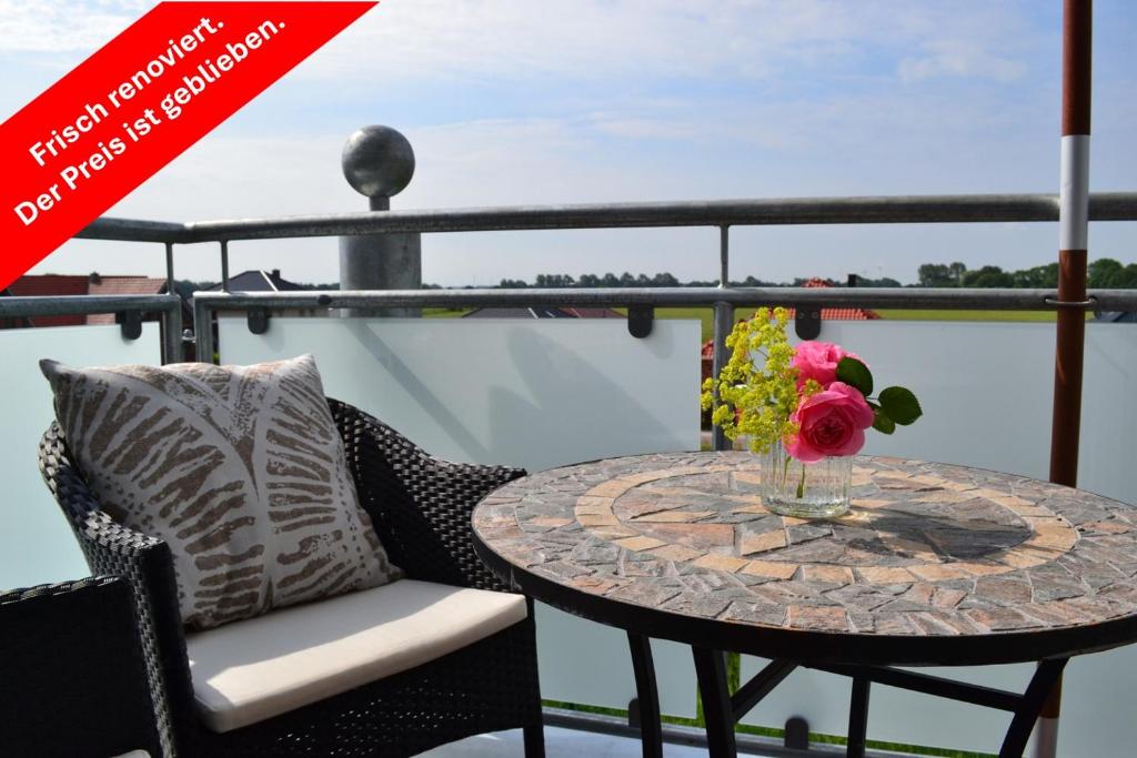 a table with a vase of flowers on a balcony at Steuerbord in Horumersiel