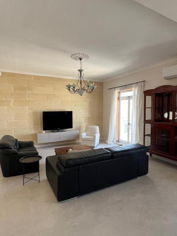 a living room with a black couch and a tv at Spacious & Central 3-Bedroom Apartment Close to the Sea in Taʼ Xbiex