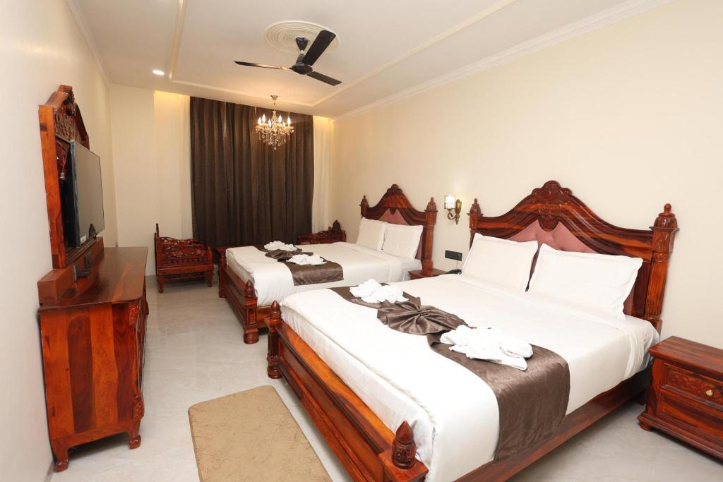 a hotel room with two beds and a flat screen tv at Hotel Shringar Mahal Vrindavan in Chhatikara