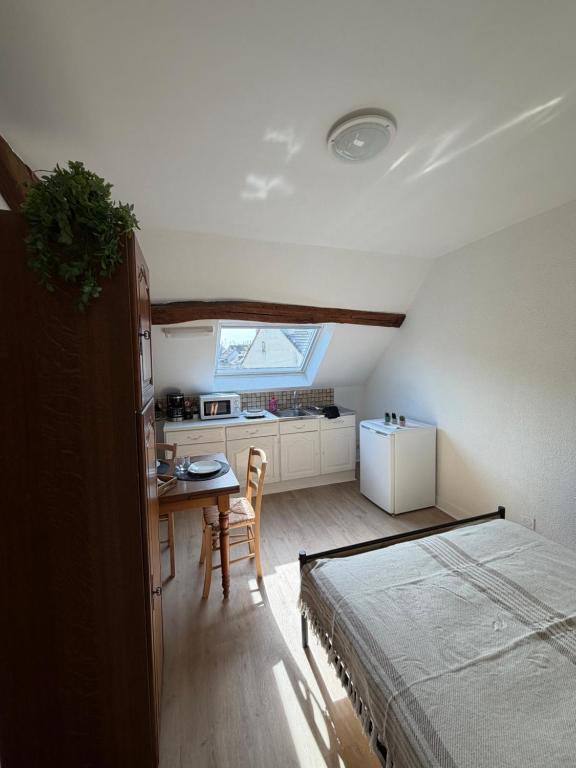 a bedroom with a bed and a table and a kitchen at Studio 16 proche du PAL in Dompierre-sur-Besbre