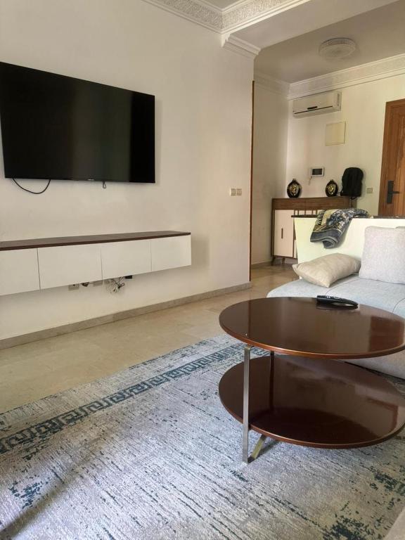 a living room with a tv and a coffee table at Résidence Al kawtar, Mimosa Appartement in Ben Slimane