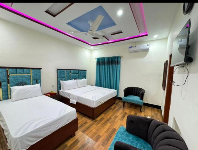 a room with two beds and a tv and a couch at Rose Family Lodges in Islamabad