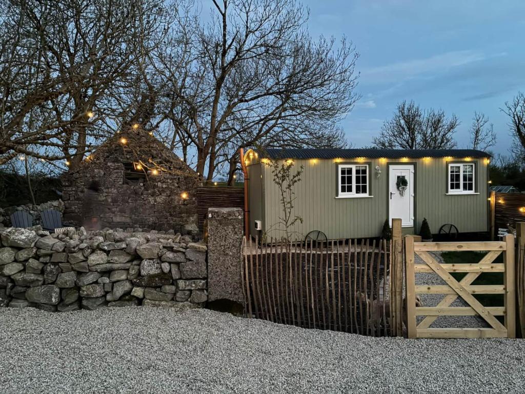 a tiny house with a stone wall and a fence at Shepherds Hut Galway in Galway