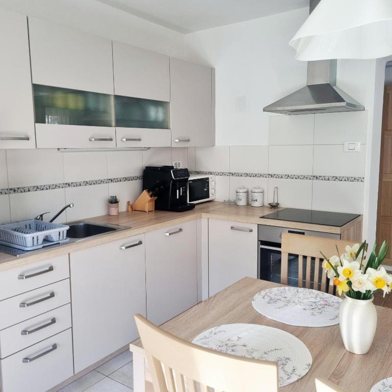 a kitchen with white cabinets and a wooden table at Apartment Drejca in Kobarid