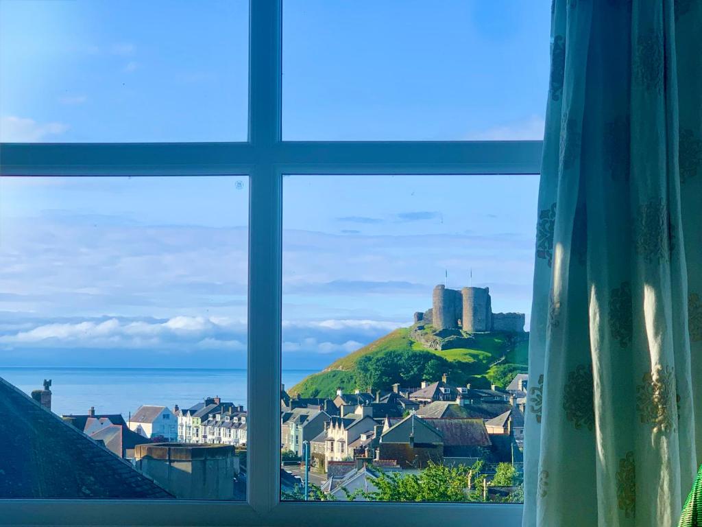 a window with a view of a town and a castle at Rooms At Greystoke in Criccieth