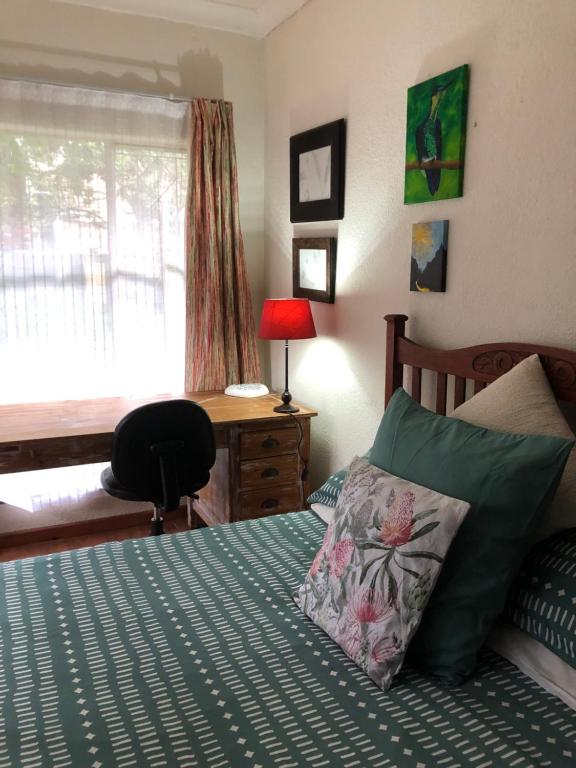 a bedroom with a bed with a desk and a chair at Knowles Nook Self-catering in Klerksdorp