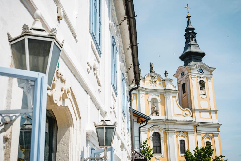 a church with a clock tower behind a building at KOKORO am Kirchplatz in Sankt Veit am Vogau