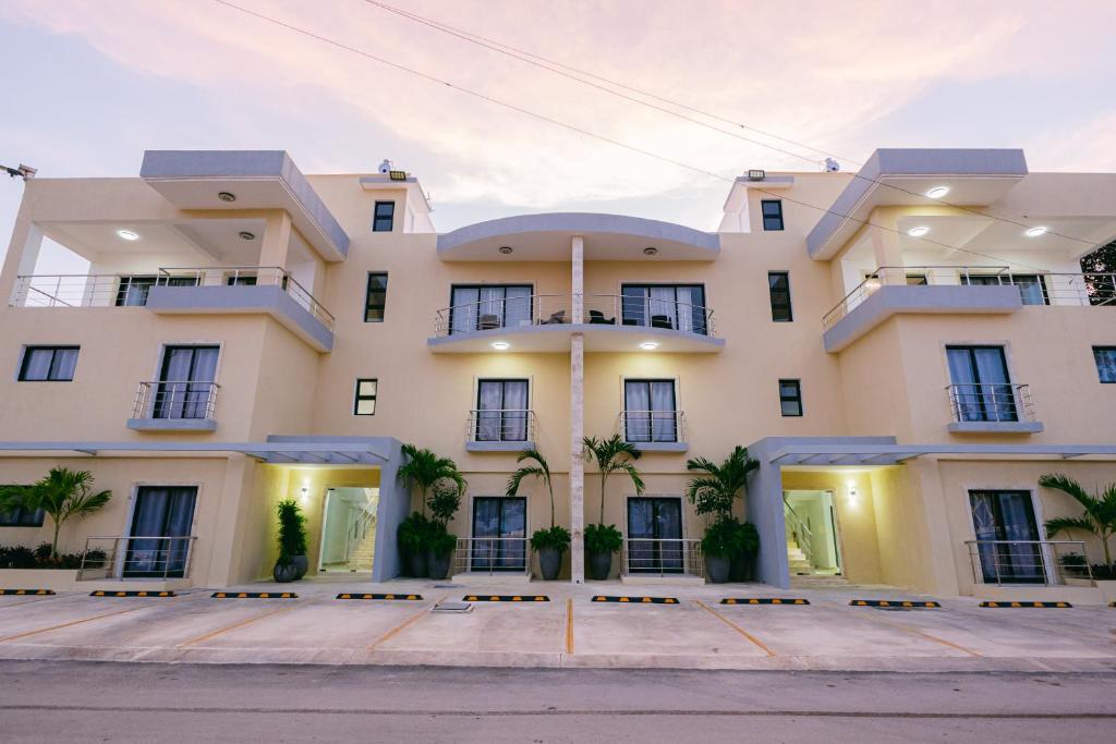 a large white building with palm trees in front of it at Arena Aparta Hotel in Punta Cana