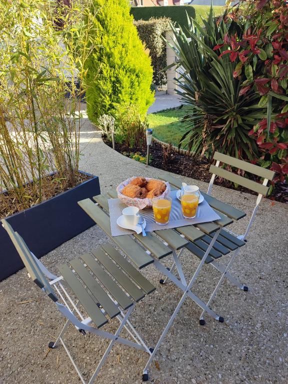 a picnic table with a basket of bread and two drinks at Studio Beauvais avec terrasse privative calme & tout confort in Beauvais