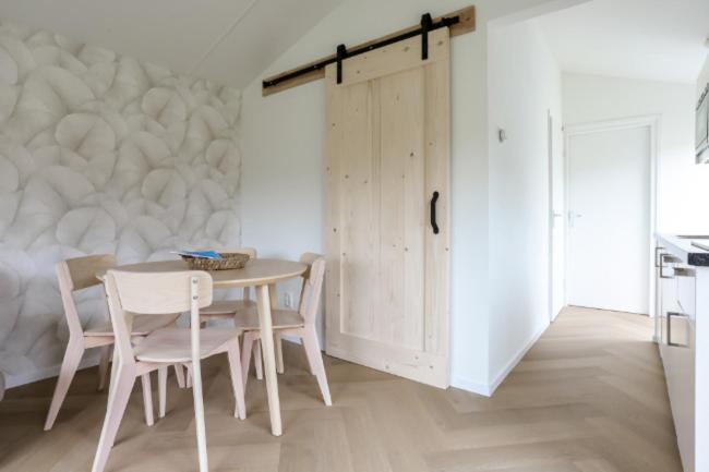 a white dining room with a table and chairs at Rekerlanden 270 in Warmenhuizen