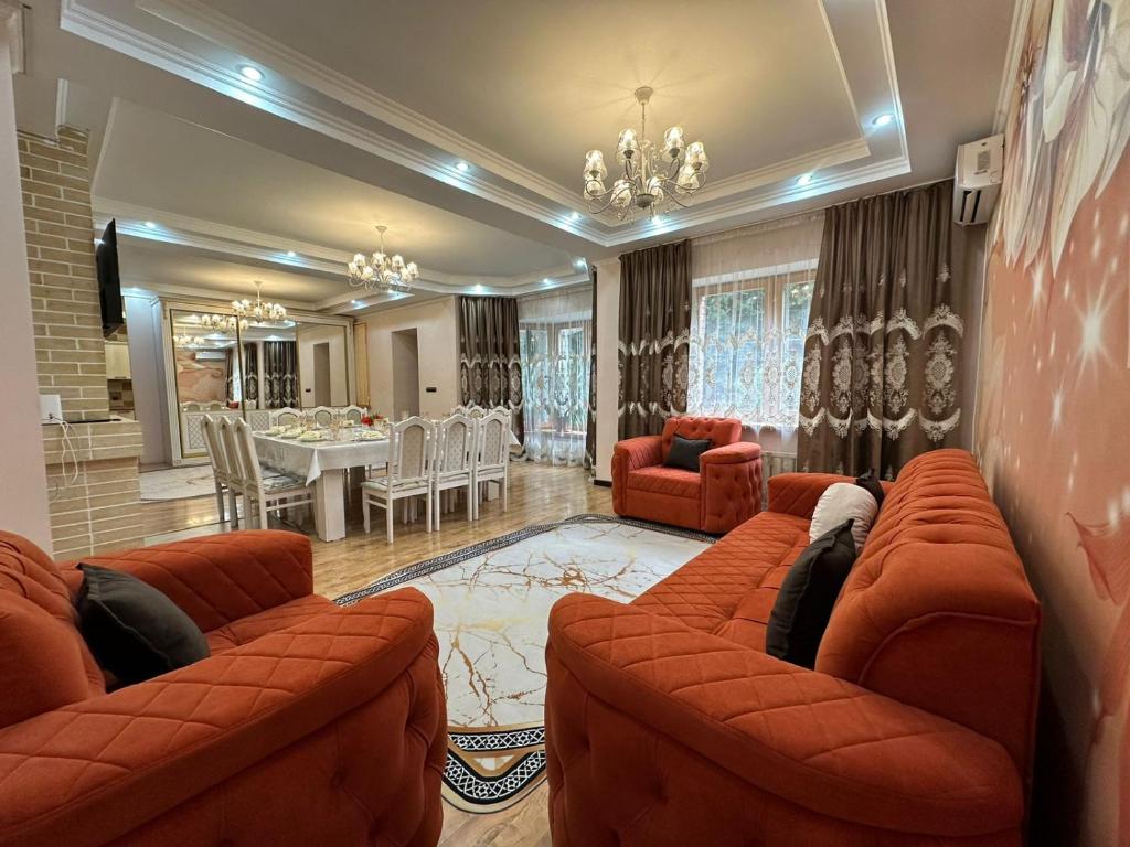 a living room with orange couches and a dining room at Гостевой дом Ласточка 2 in Almaty