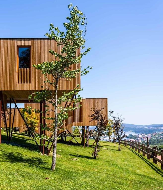 a wooden house on a hill with a tree at Cabanas de Canduas in Cabana de Bergantiños