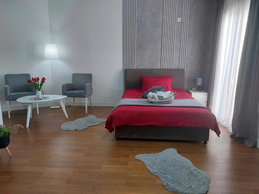 a bedroom with a red bed and a table and chairs at Aria Apartmani in Podgorica