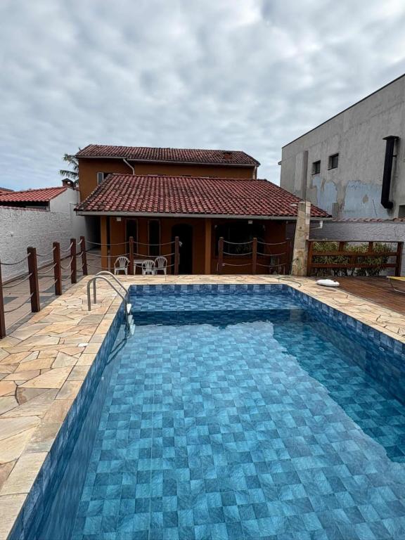 a large blue swimming pool in front of a house at Casa com piscina in Bertioga