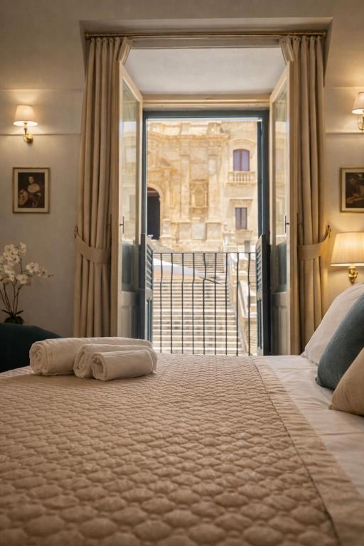 a bedroom with a large bed and a balcony at Immacolata Rooms in Noto