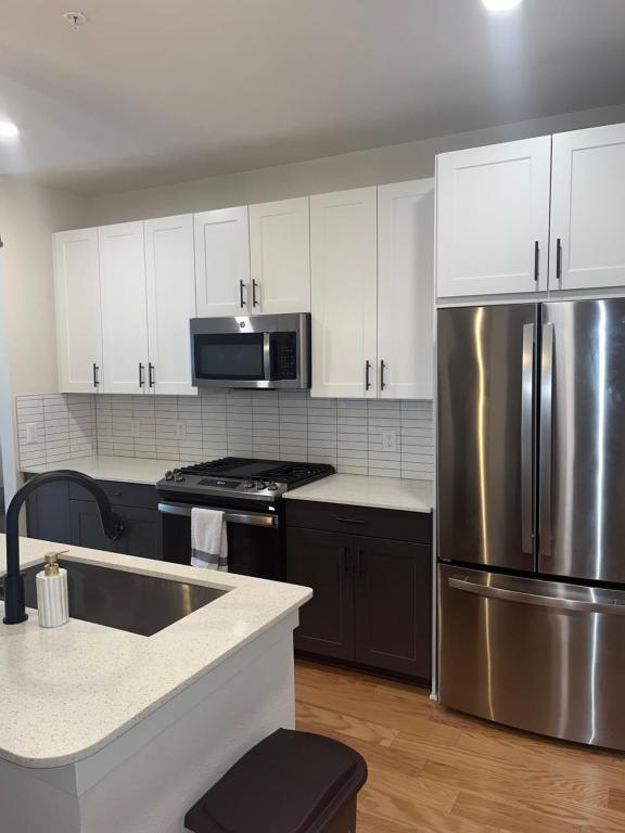 a kitchen with white cabinets and a stainless steel refrigerator at Arthouse in Houston
