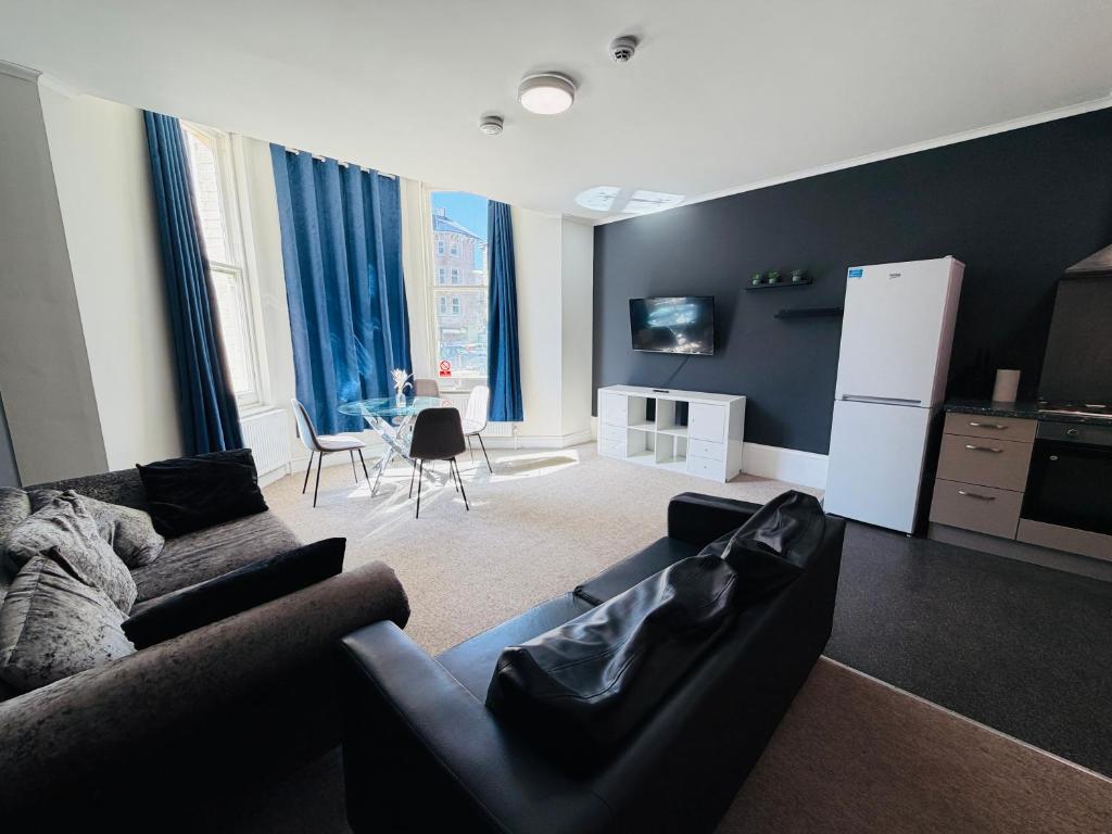 a living room with a couch and a refrigerator at First Avenue Apartments Stylish 2 & 3 Bed Flats in Central Hove in Brighton & Hove