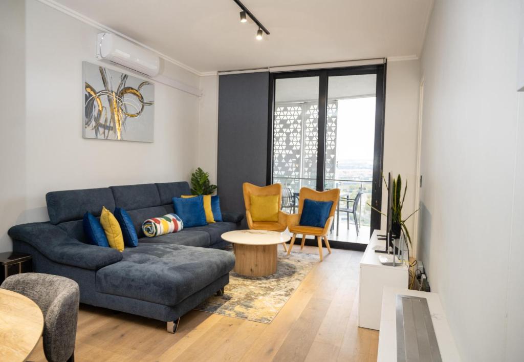 a living room with a blue couch and a table at Elegant-World Ellipse Waterfall in Midrand