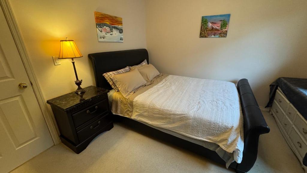a bedroom with a bed and a lamp on a night stand at Warm house3 in Coquitlam