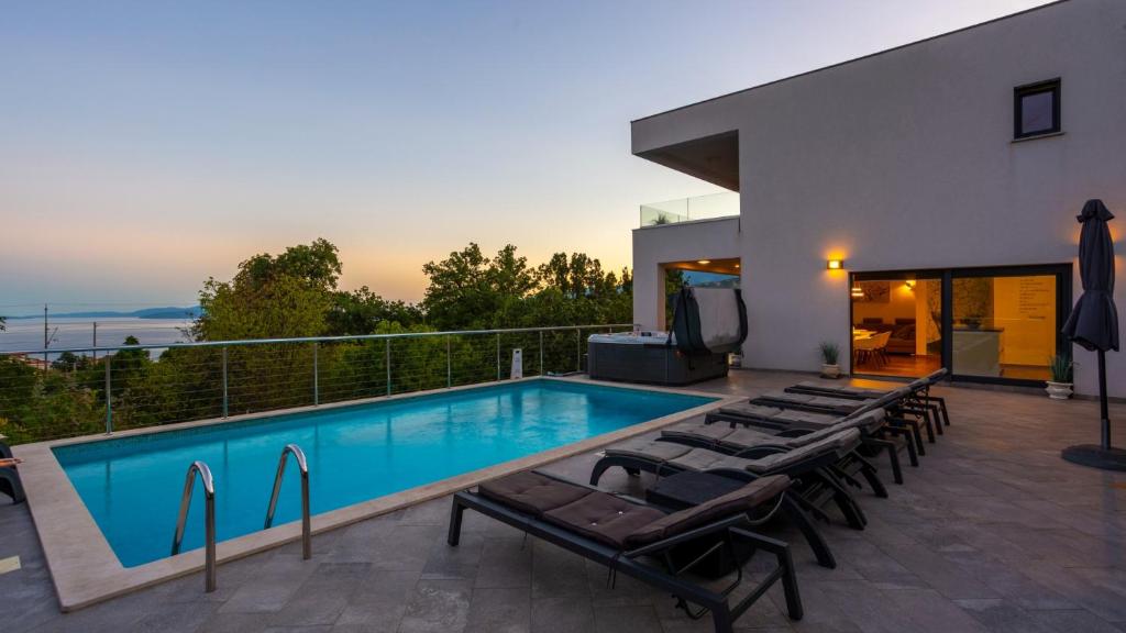 a swimming pool with lounge chairs next to a house at Villa Angello in Matulji