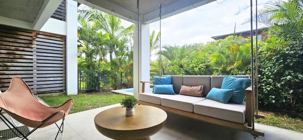 a porch with a swinging couch and a table and chairs at Tropical - Resort - Spa - Pool & Garden in Grand-Baie