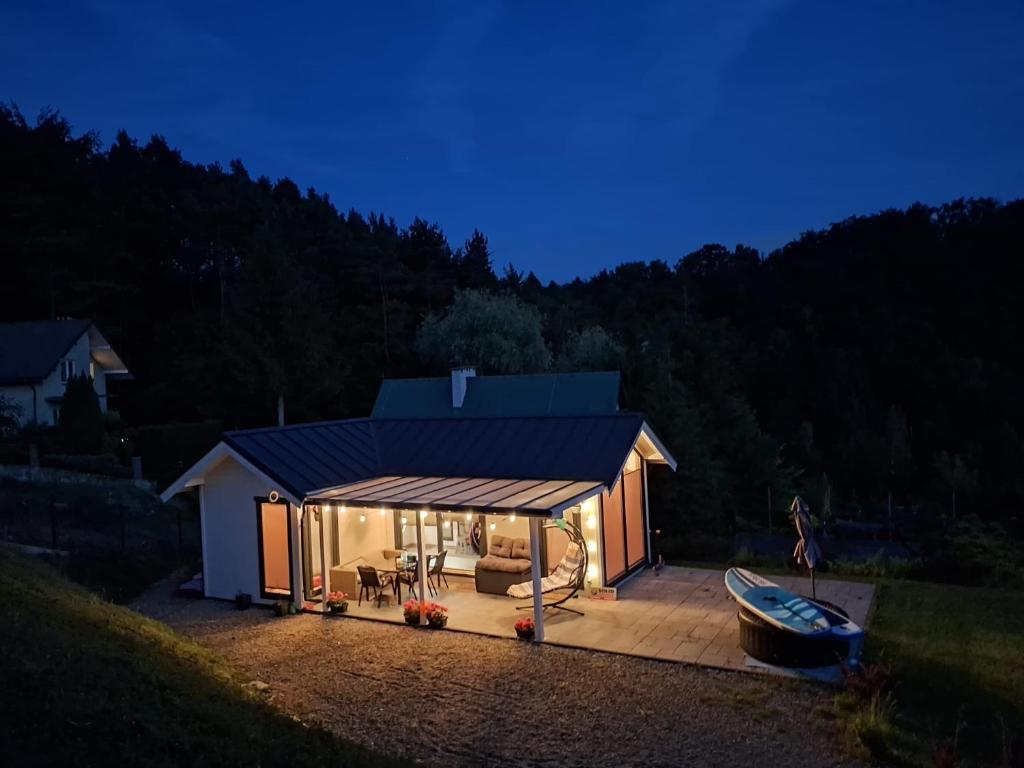 a house with a deck with a boat in it at Slow Lake House Koszarka in Gródek Nad Dunajcem