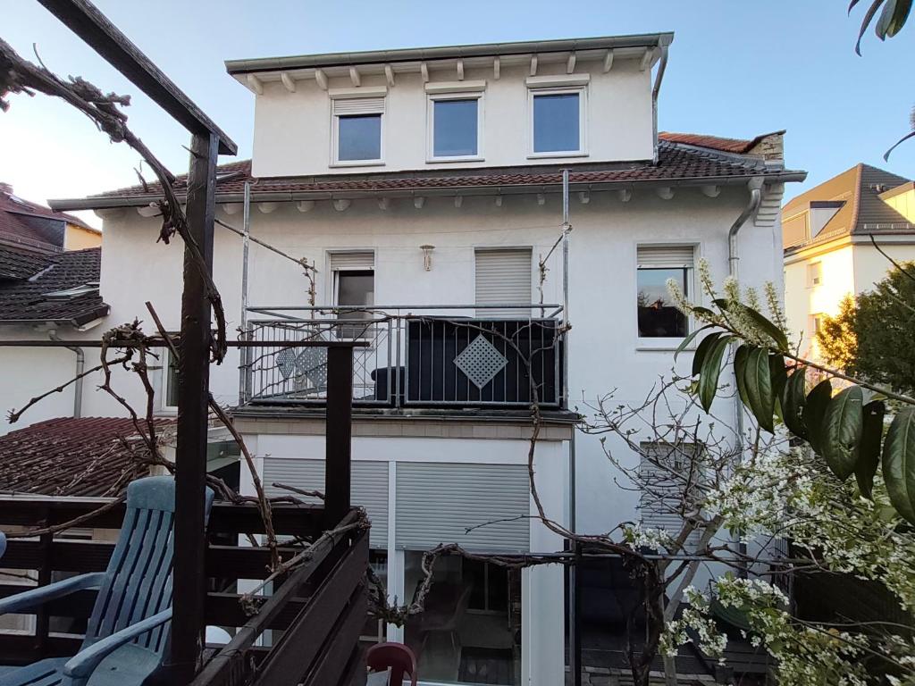 a white house with a balcony and a blue chair at Fair-Hostel in Darmstadt